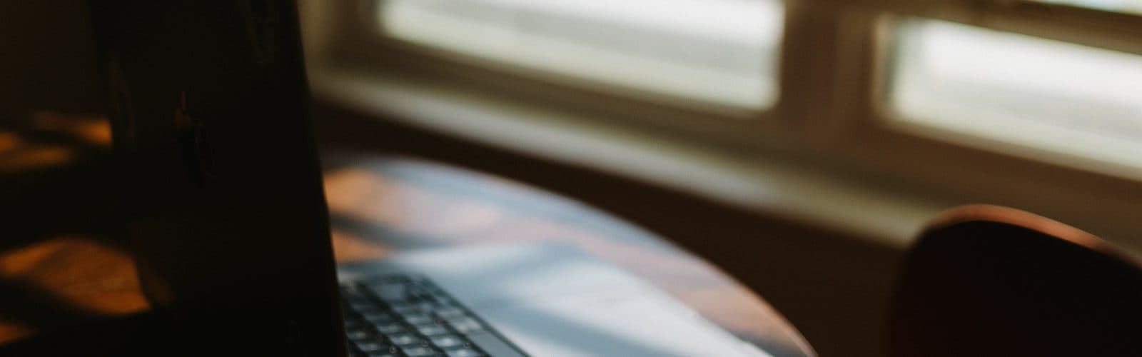 Laptop on a desk by a sunlit window